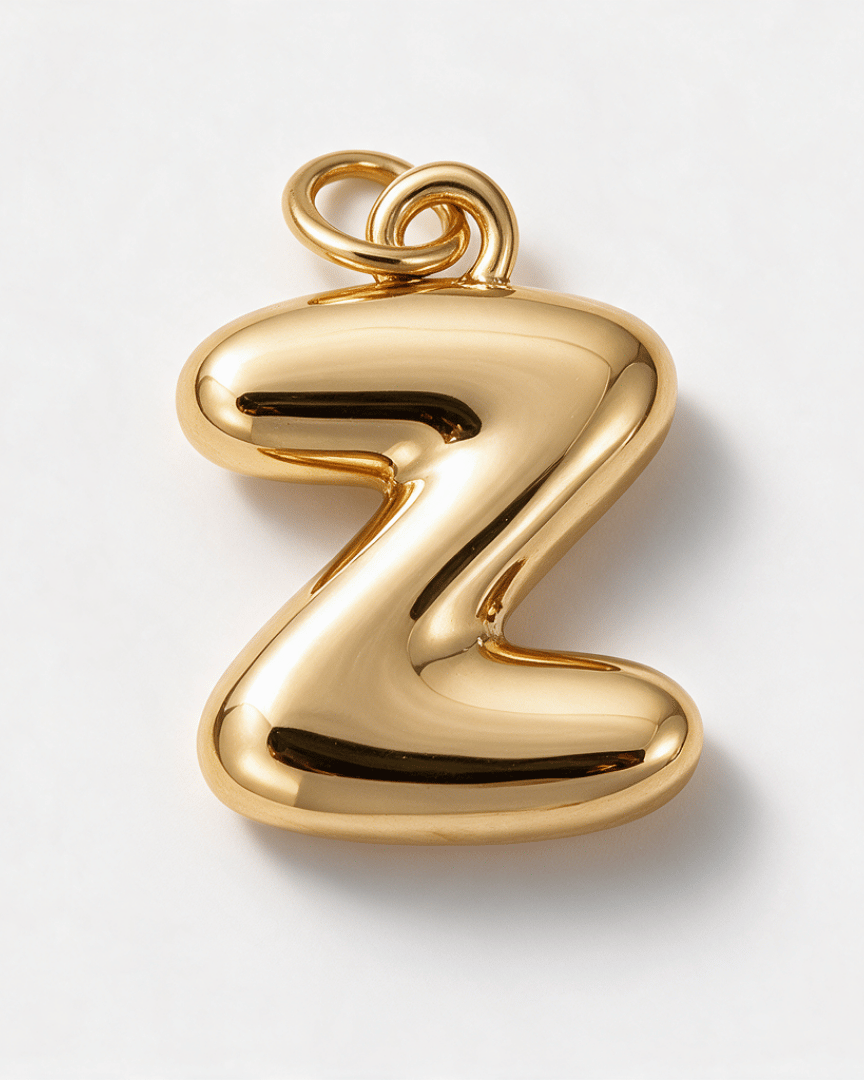 A polished gold pendant shaped like the lowercase letter 'z', shown on a clean white background.