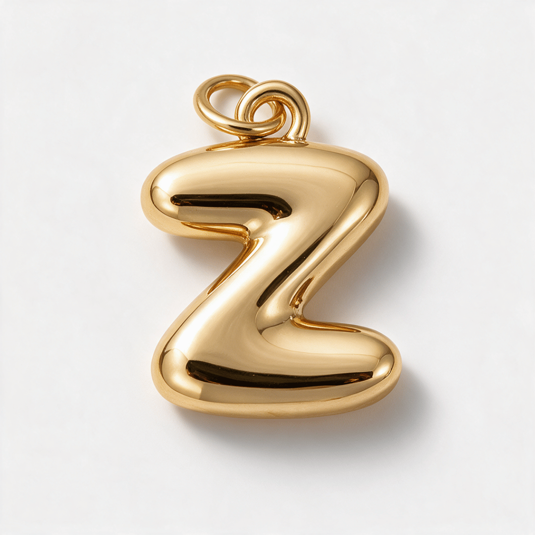 A polished gold pendant shaped like the lowercase letter 'z', shown on a clean white background.
