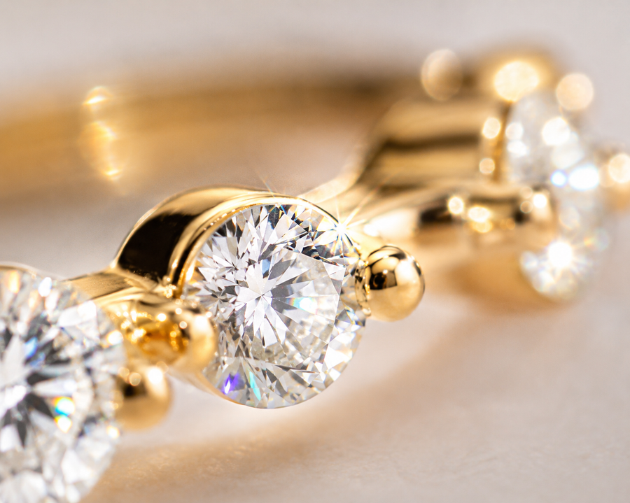 Close-up of gold earrings with clear gemstones on a light background