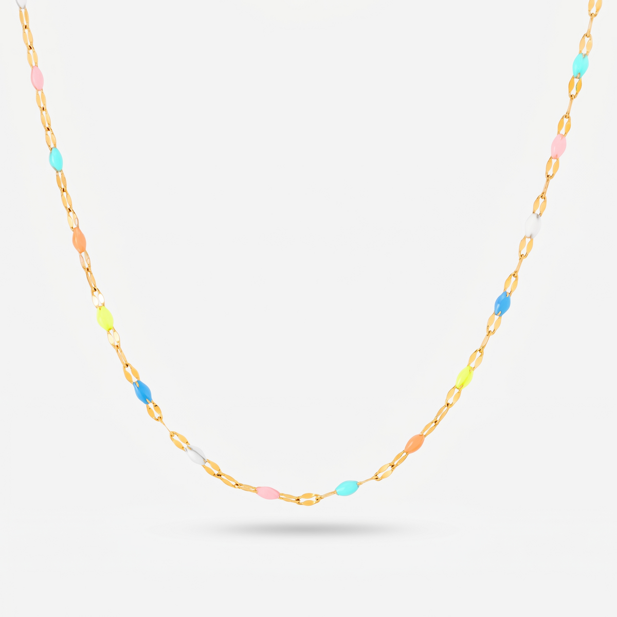 A delicate gold chain necklace featuring small, evenly spaced pastel-colored oval beads in blue, pink, yellow, and white, displayed against a clean light gray background.