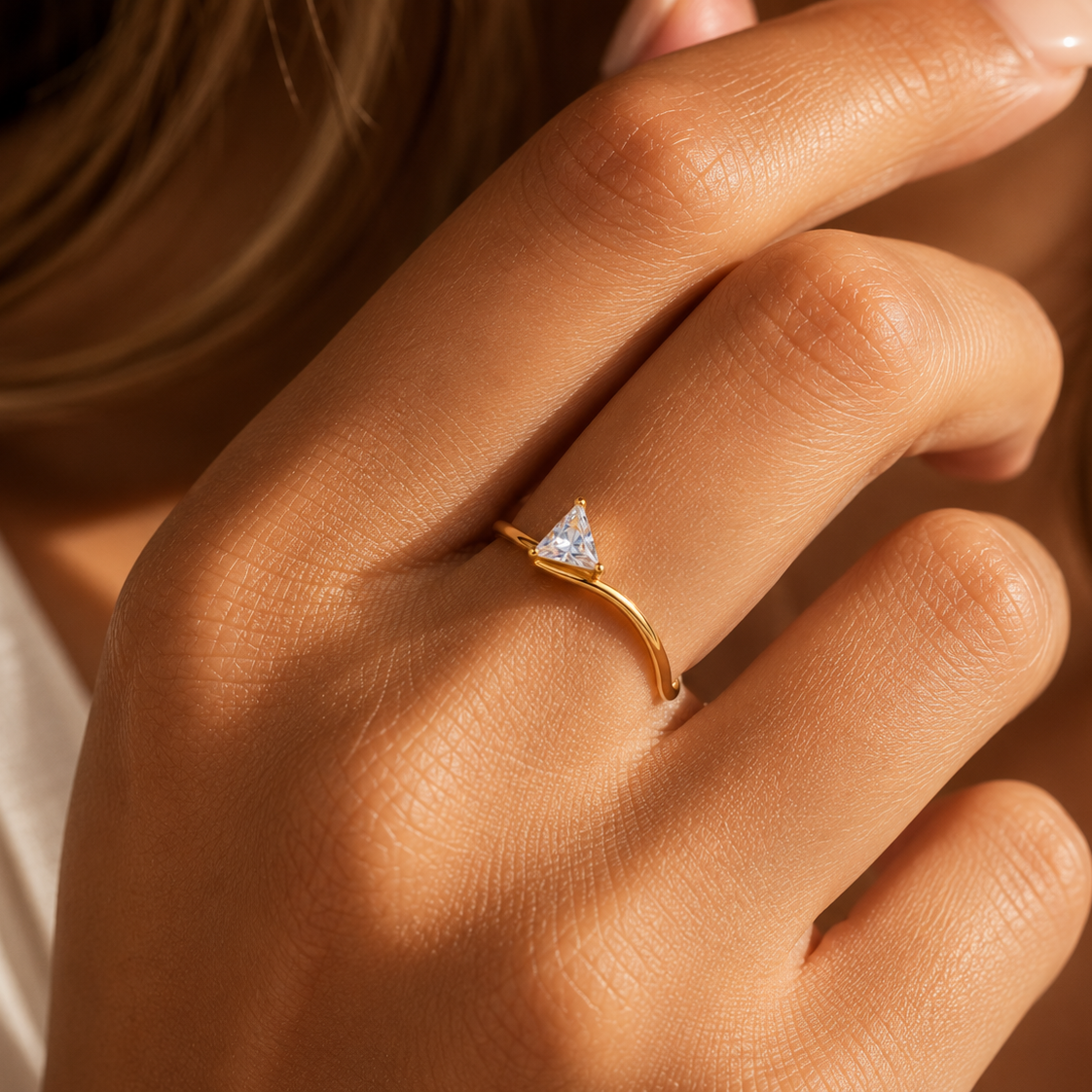 Gold ring with a triangular diamond on a hand